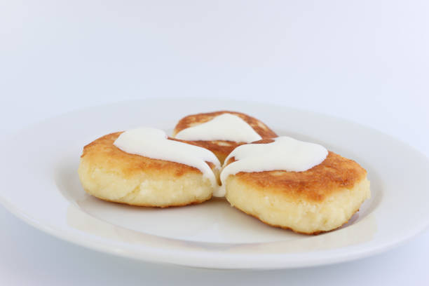 Delicious, ruddy cheesecakes covered with sour cream on a white plate.