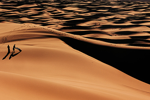 Two persons relaxing on a sand dune near Erg Chebbi, Sahara desert, Marocco