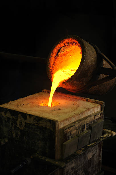 Foundry - molten metal poured from ladle into mould stock photo