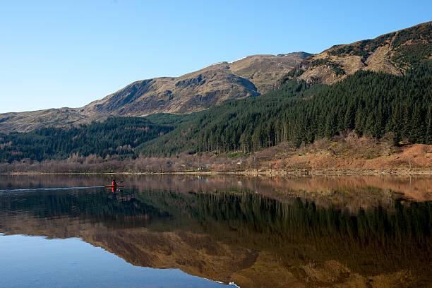 istock Canoeist paddles across mirror surfaced lake 177280550