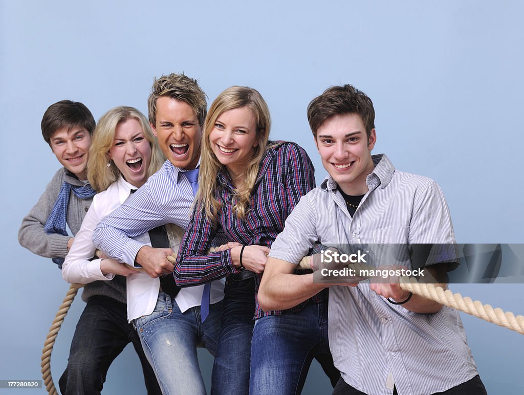 Trabajo en equipo: Jóvenes playing tug-of-war - Foto de stock de Lucha de la cuerda libre de derechos