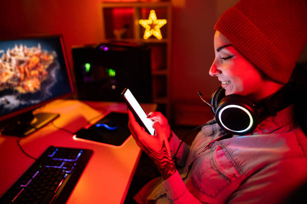 istock Young Caucasian female gamer using mobile phone, while playing video games on PC 1772810266