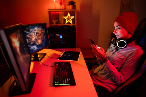 istock Caucasian female gamer using mobile phone, while playing video games on PC 1772810813