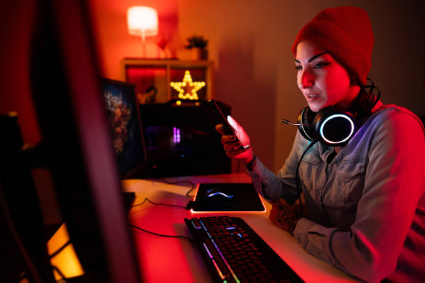 istock Urban Caucasian female gamer using mobile phone, while playing video games on PC 1772811393
