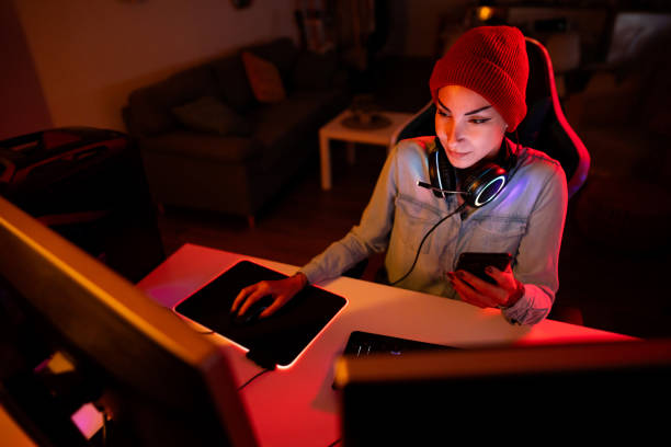 istock Young Caucasian female gamer using mobile phone, while playing video games on PC 1772811398