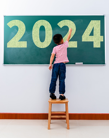 Child written new year number 2024 on the blackboard