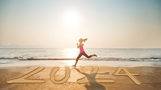 Young woman running on new year number 2024 beach