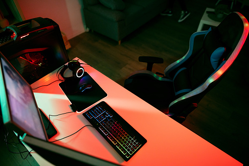 Modern computer set up, with the video game on the device screen, in the gamer room, with red LED light