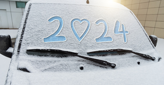 New year 2024 with heart shape written on car windshield