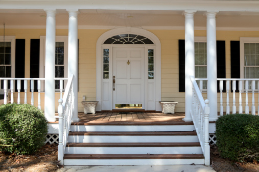 front porch on yellow home with white columns, steps leading up to door with white door and brass kickplate, taken with Canon 5D Mark II digital camera