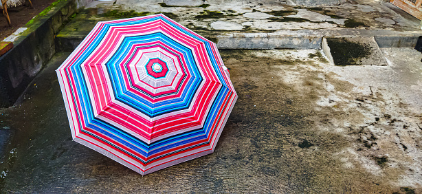 Umbrella on cement floor after rain.