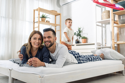 Portrait of parents lying in bed while their son is playing
