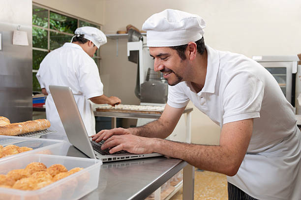 Baker with computer at bakery stock photo