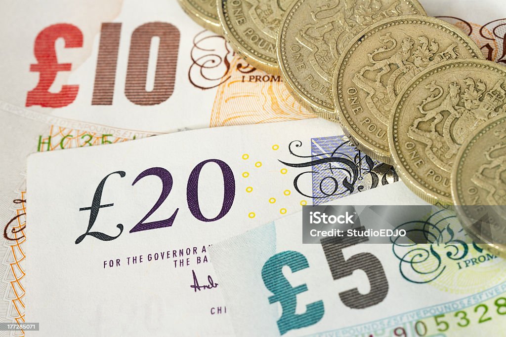 UK Bonknotes And One Pound Coins A line of UK One Pound Coins on top of UK Banknotes (£5, £10, £20) British Pound Note Stock Photo