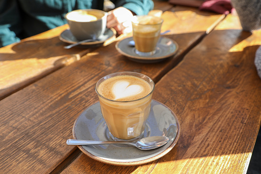 Flat white coffees with heart foam on table in sunshine