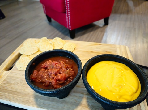 Salsa And Queso Dip With Chips Sitting On A Wood Cutting Board