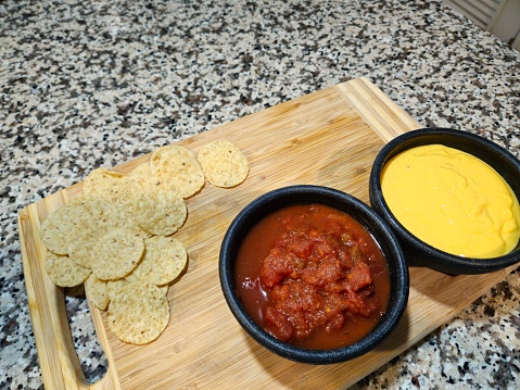 Salsa And Queso Dip With Nacho Chips Sitting On A Wood Cutting Board