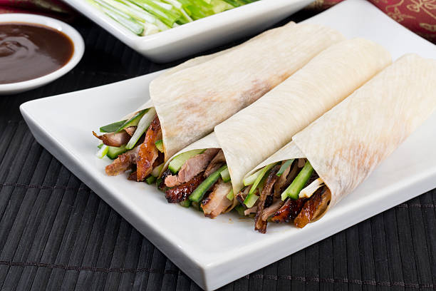 Peking Duck Wrap Chinese peking duck wrapped in pancakes with cucumber, spring onions and hoisin sauce. hoisin sauce stock pictures, royalty-free photos & images