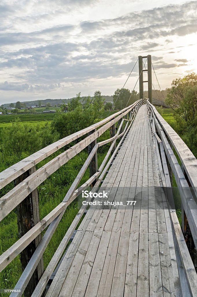 Passerella in legno vecchio lungo pendente con guide contro il tramonto sullo sfondo - Foto stock royalty-free di Ambientazione esterna