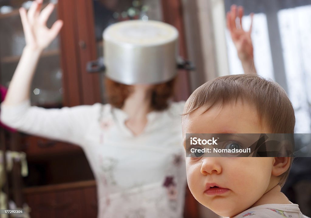 Scared baby against crazy mother Portrait of scared baby against crazy mother with pan on head Bizarre Stock Photo