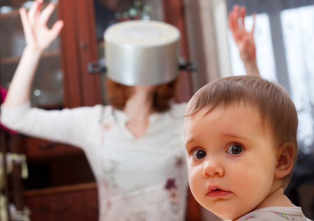 Scared baby against crazy mother Portrait of scared baby against crazy mother with pan on head fear in babies stock pictures, royalty-free photos & images