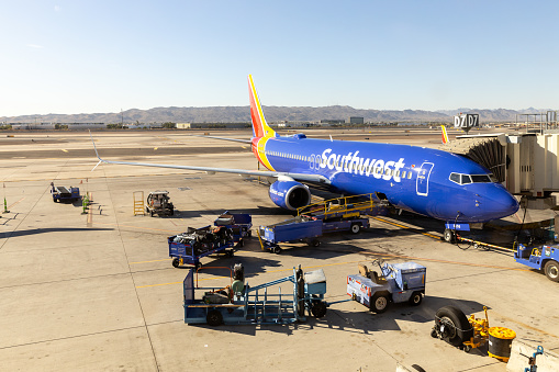 Phoenix, AZ, USA - October 29, 2023: The Phoenix Sky Harbor International Airport runway with a Southwest Airlines plane being loaded at a gate and mountains in the distance.