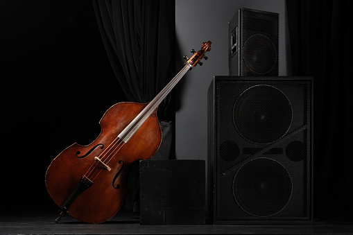 Beautiful classic double bass on the concert stage with acoustic speakers. Acoustic wooden double bass on stage. Brown Contrabass. Wooden musical string instrument.