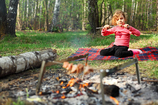 istock Girl sits near campfire with grill and eats shish kebab 177295186