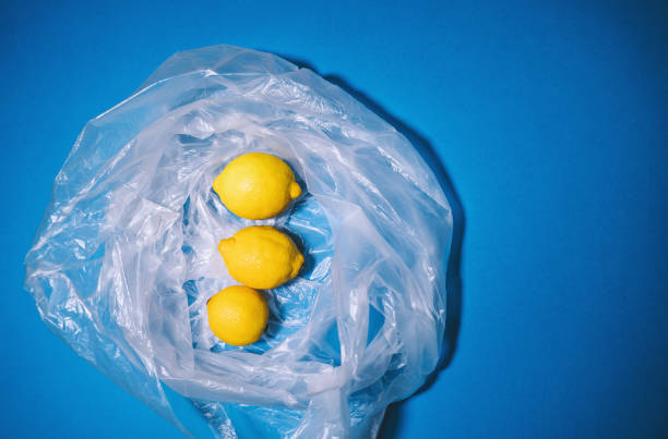 istock Lemon fruits in transparent plastic bag on blue background. Concept about plastic pollution, microplastics in environment, problems in ecosystems. Minimal style, flat lay, top view, copy space. 1772955709