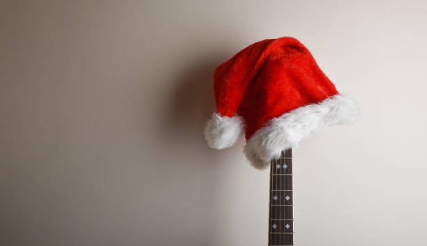 istock Guitar neck with santa hat leaning on isolated white wall 1772964541