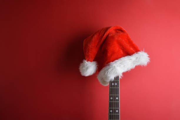 istock Guitar neck with santa hat leaning on isolated red wall 1772964547