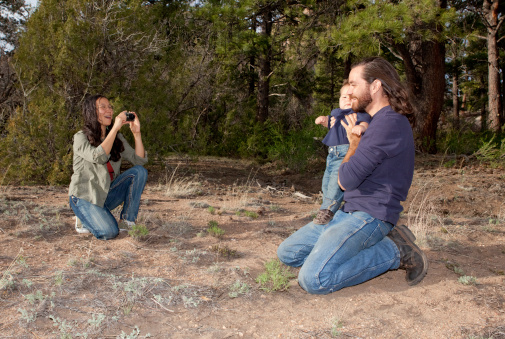 Mother taking a picture of father and son outdoors in nature