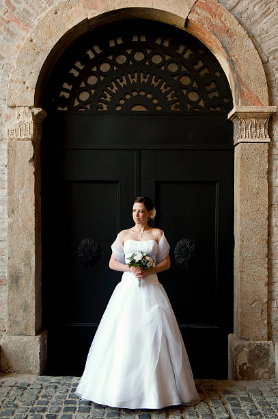 novios de pie contra de un antiguo arco metálico de entrada. - bride women standing beauty in nature fotografías e imágenes de stock