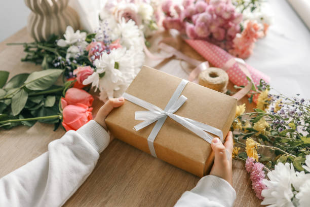 istock Gift box in hands with flowers at home 1772976538