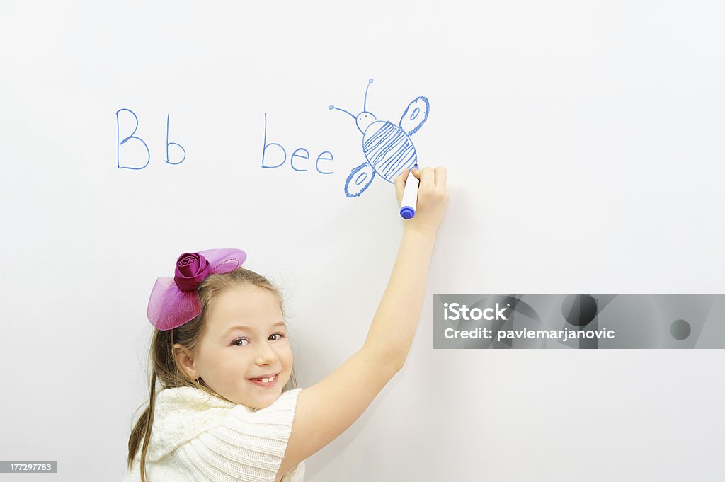 Sonriente niña en edad escolar aprender a escribir letra B - Foto de stock de Escribir libre de derechos
