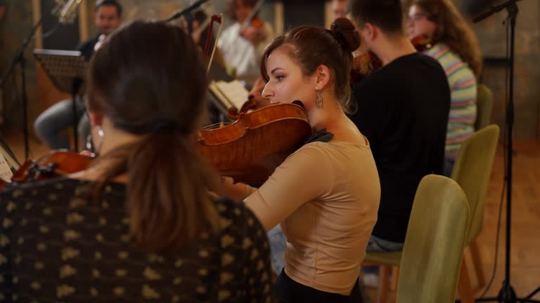 Group of music students playing violins - rehearsing classical music