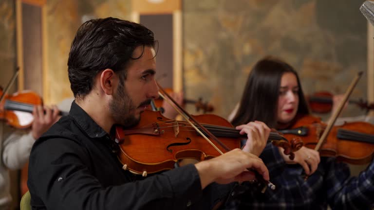 Young adult music orchestra students rehearsing music in studio