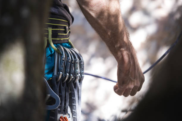 Athletic man climb rock with rope and carabiners, lead climbing. Row of carabiners in a climb harness. stock photo