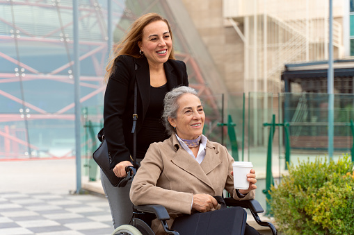 Senior Female Employee in Wheelchair and Her Female Colleague Spending Time Outdoors