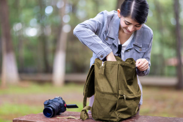 Young woman looking for another lens for her camera in her backpack