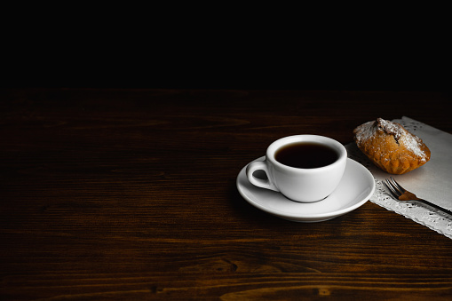 Muffin with white cup of black coffee on a dark wooden background