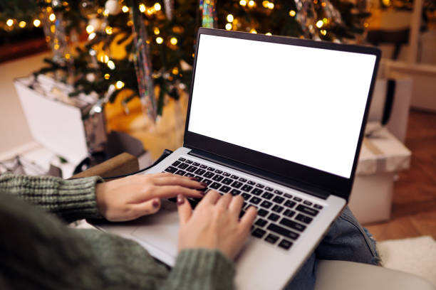 istock woman work on laptop computer with blank display screen with mockup copy space. home interior decorated for Christmas celebration with Christmas tree and garland lights. 1773037088