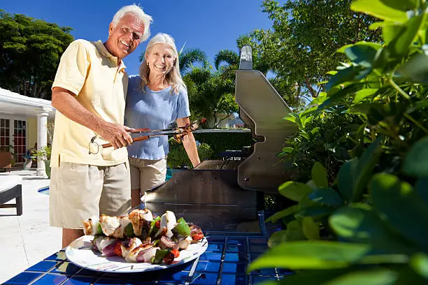 Photo of Upscale mature couple barbecuing in a lush treed environment