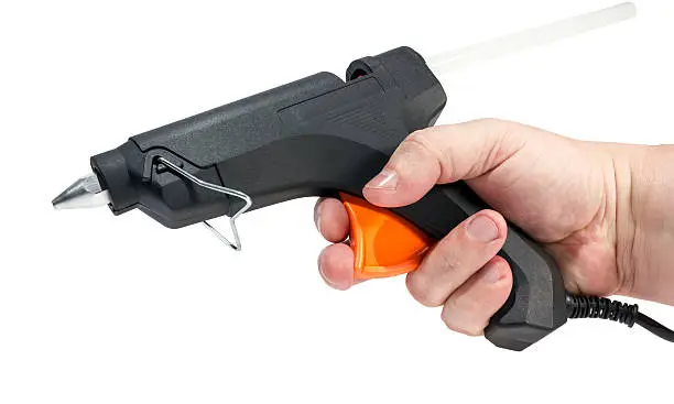 Electric hot glue gun in hand isolated on a white background.