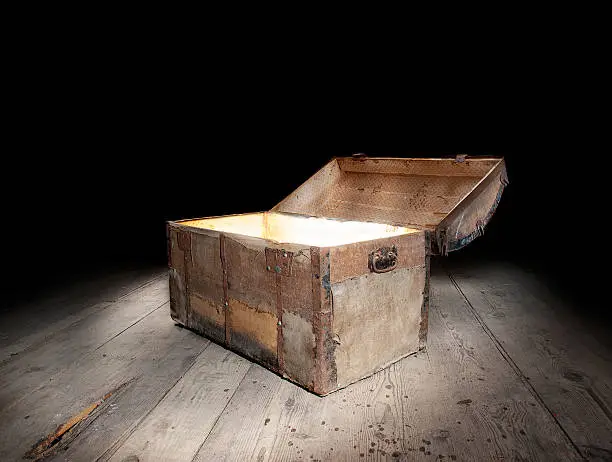 Ancient wooden treasure chest with the strong glow from inside.