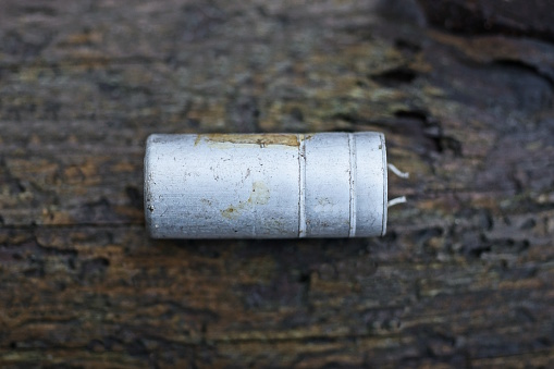 one white old metal electronic part barrel lies on a gray table