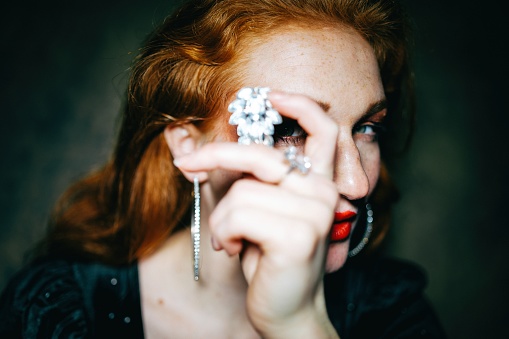 Portrait of a beautiful red-haired woman with a fancy piece of jewelry.