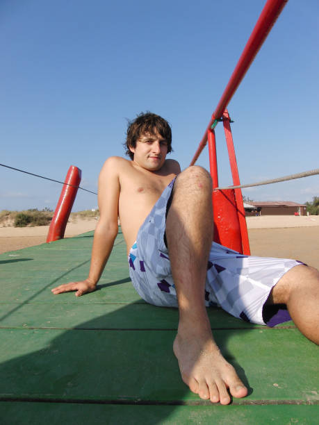 Young man on a jetty on a beach in summer waiting for his ferry in a popular beach in Cantabria, north of Spain