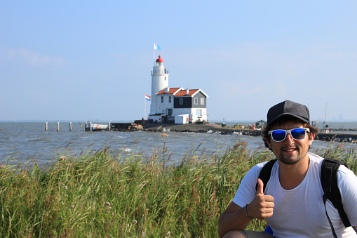 Young man during his summer holidays in Marken, Netherlands making himself a picture with Marken lighthouse