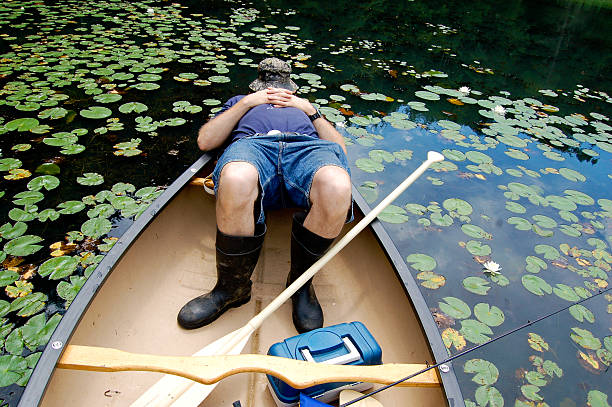 Fisherman asleep in his canoe stock photo
